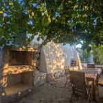Terraza exterior de Casa Joya con comedor y barbacoa bajo los árboles.